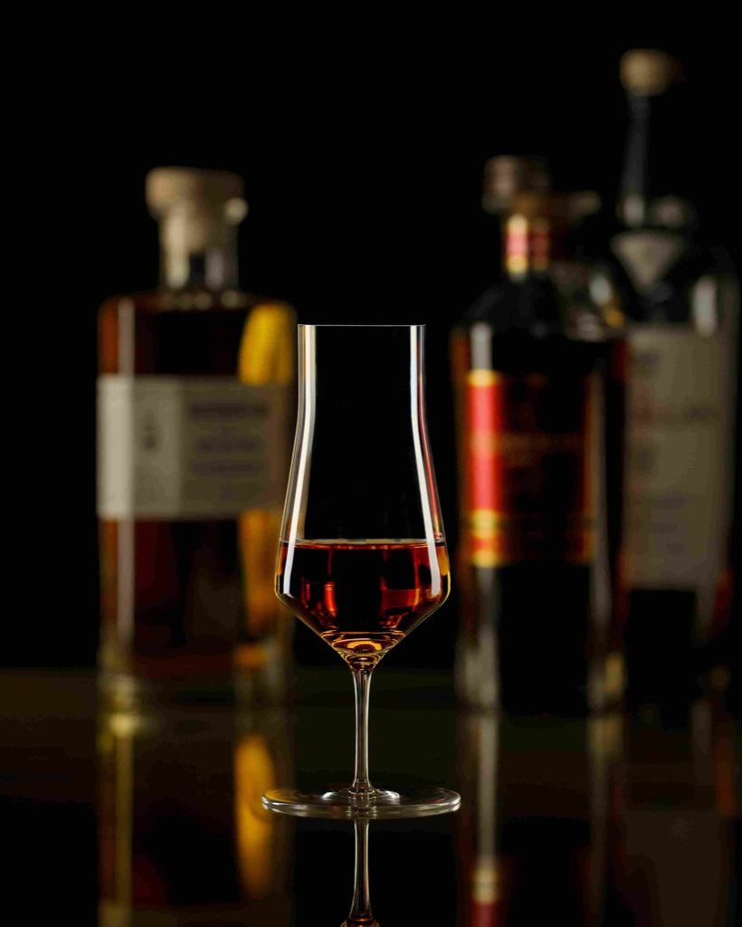 Zalto Denk'Art Cask Whiskyglas mit Whisky und Flaschen im Hintergrund
